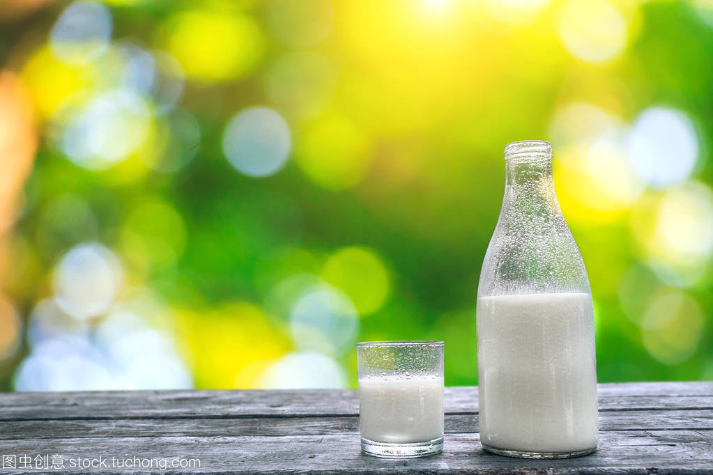 瓶和杯冷牛奶木制的桌子上。新鲜的乳制品。自然背景